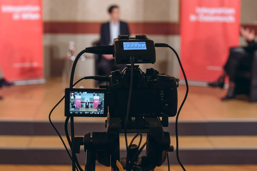 Kamera und Kontrollmonitor vor einer Konferenzbühne